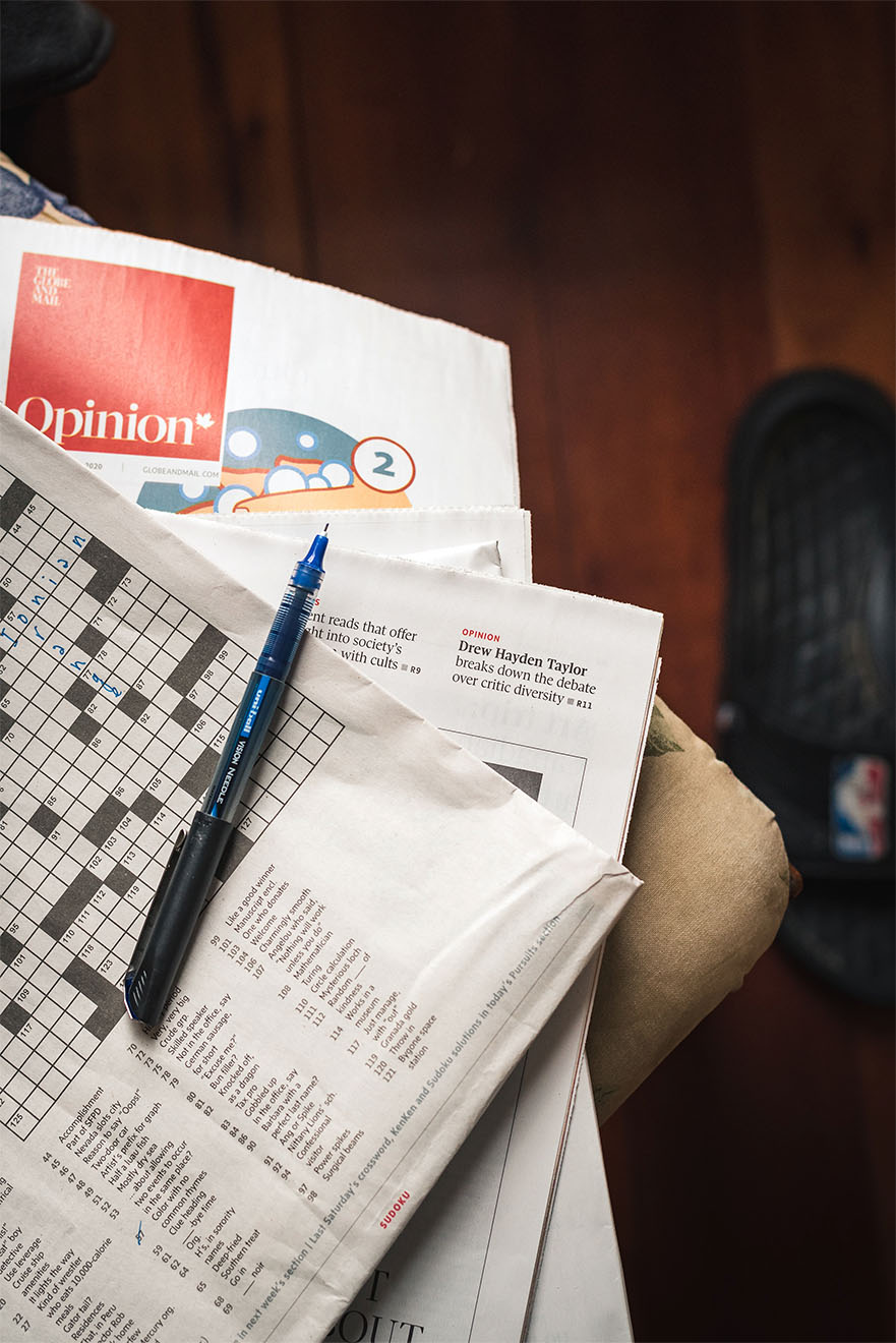 an array of newspapers and games including an in progress crossword