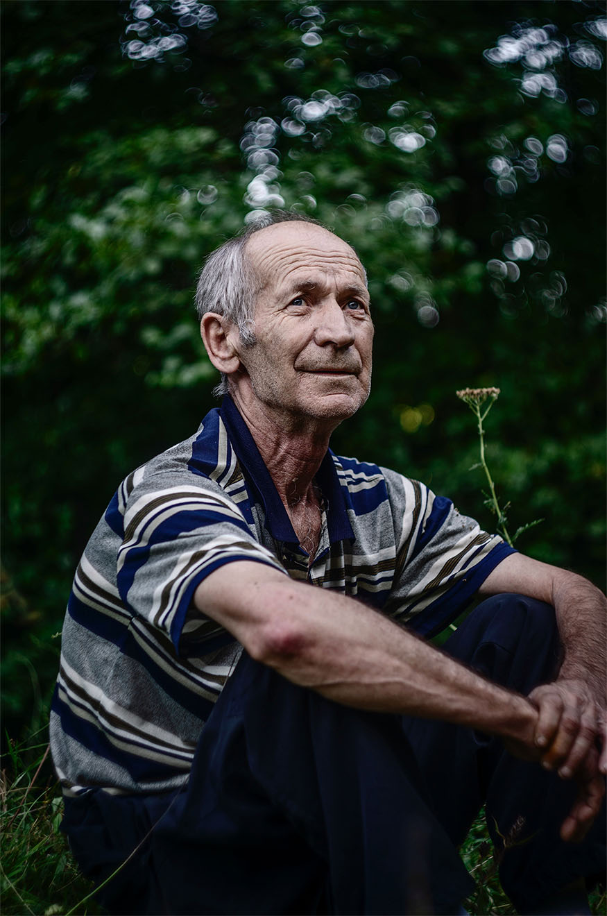 male resident sat outside hugging his legs