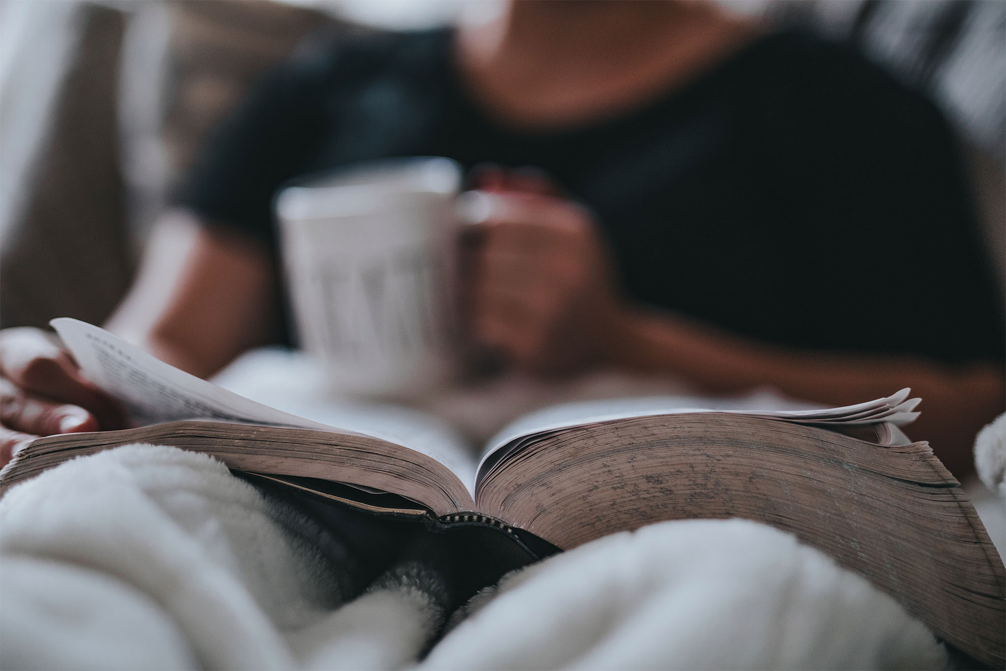 resident sat reading a book with a drink in their hand