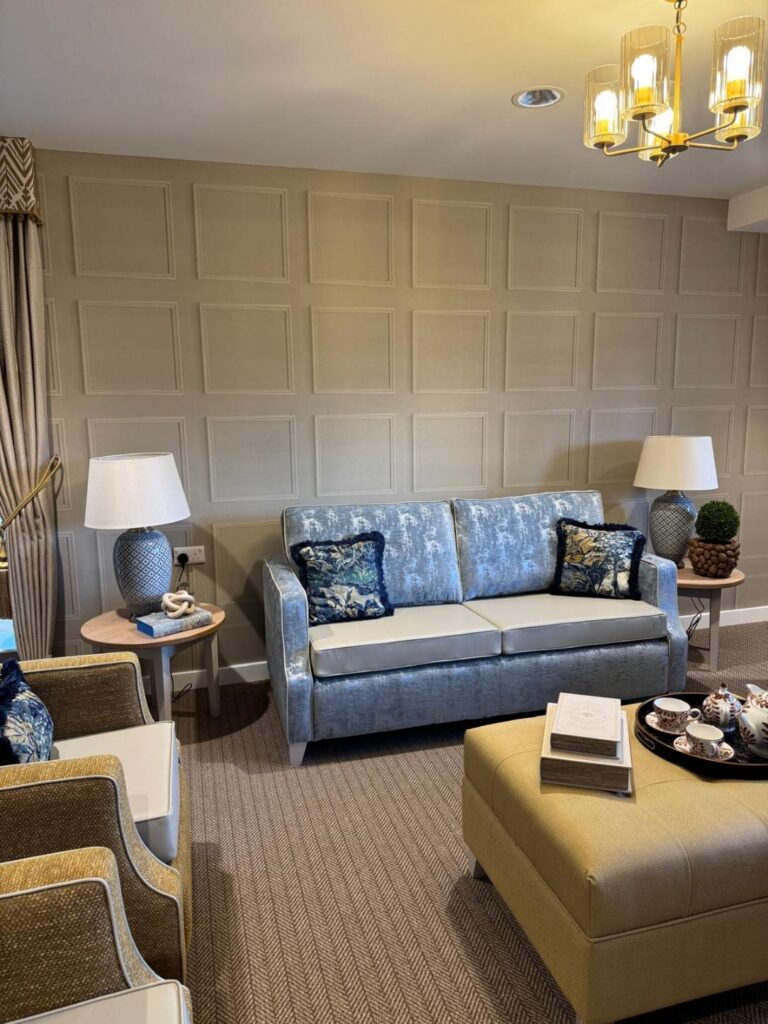 blue velvet sofa in a lounge with grey walls and blue lamps