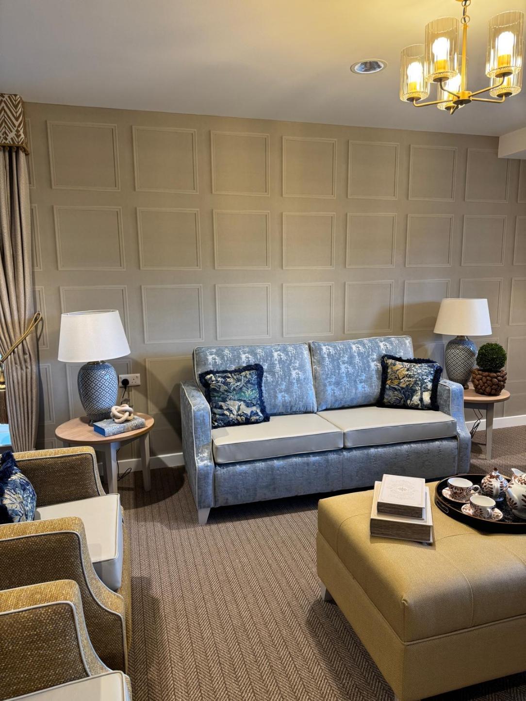 blue velvet sofa in a lounge with grey walls and blue lamps