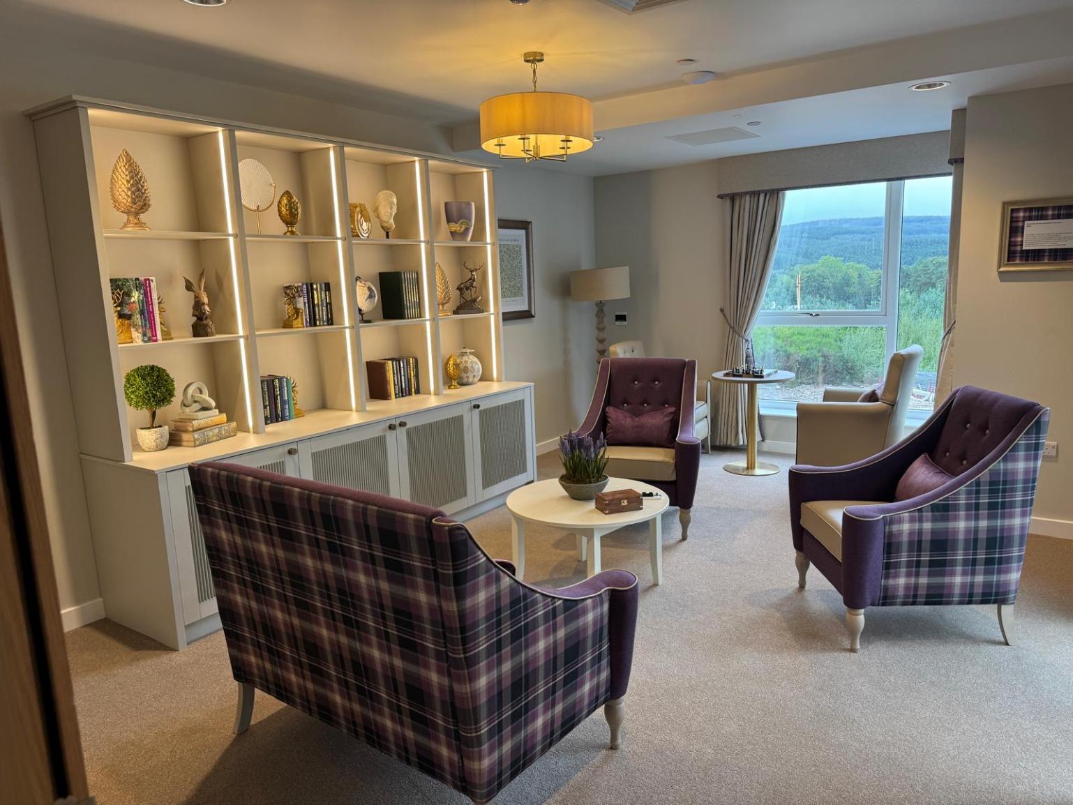 purple checkered chairs and sofas facing each other in a lounge area with a large bookshelf