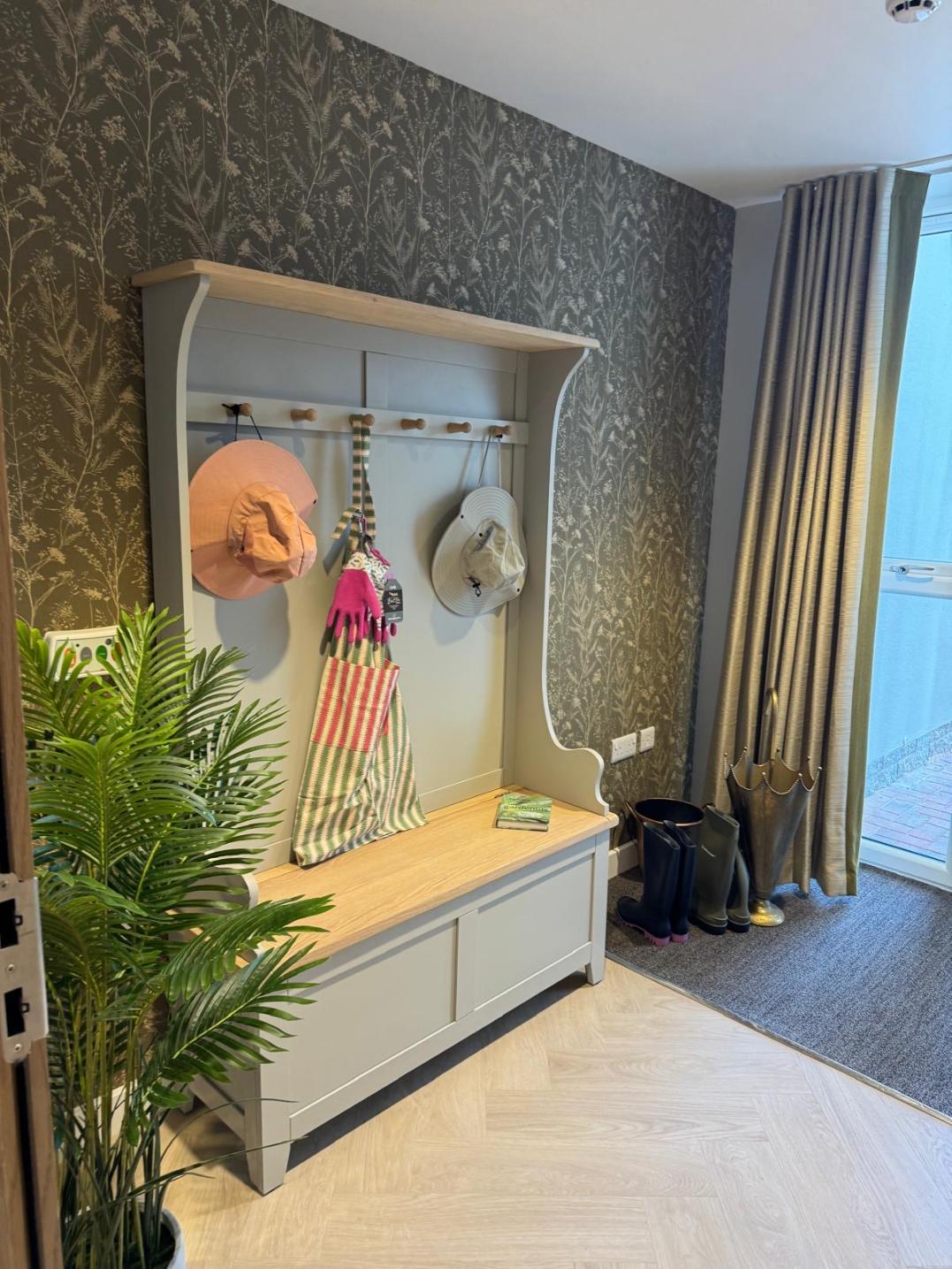 a grey wooden cabinet holding gardening gloves, an apron, and hats