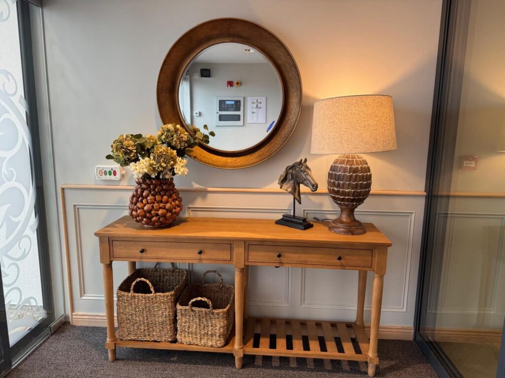 a wooden side table with lamps, flowers and a basket on it